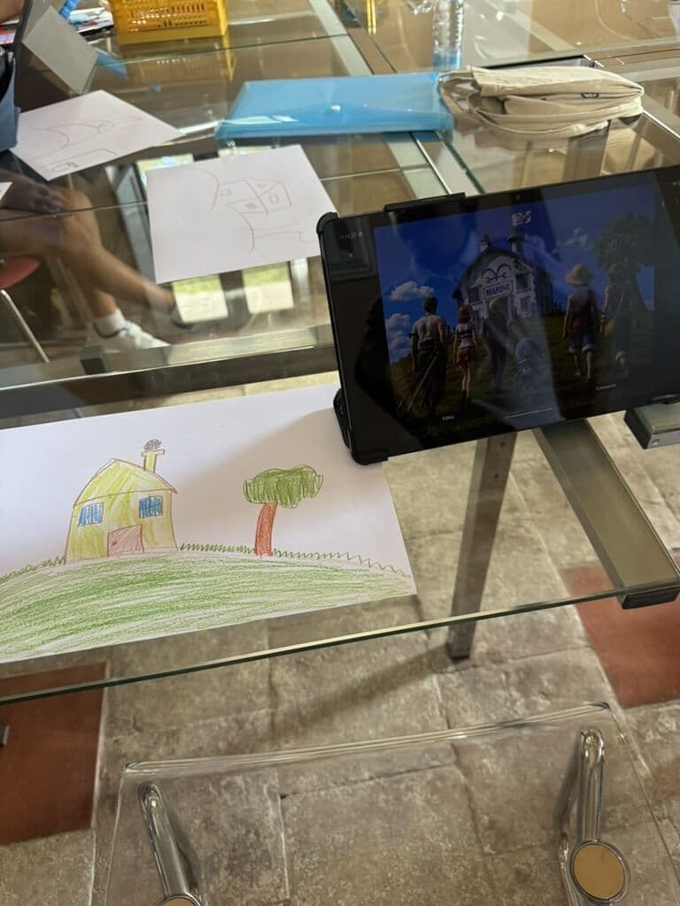 El dibujo de una casa hecho por un niño junto a una tablet que muestra la misma idea convertida en una escena con IA