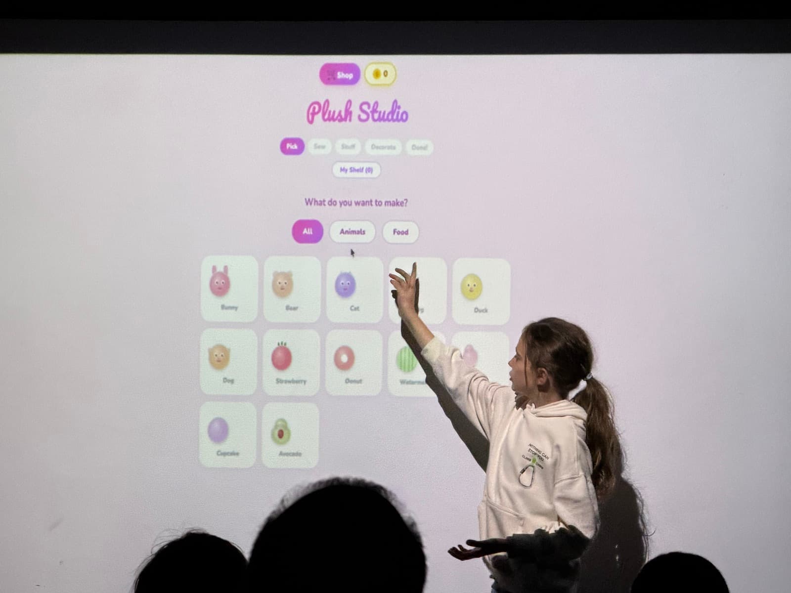 Lara presentando Plush Studio, señalando su app en la pantalla