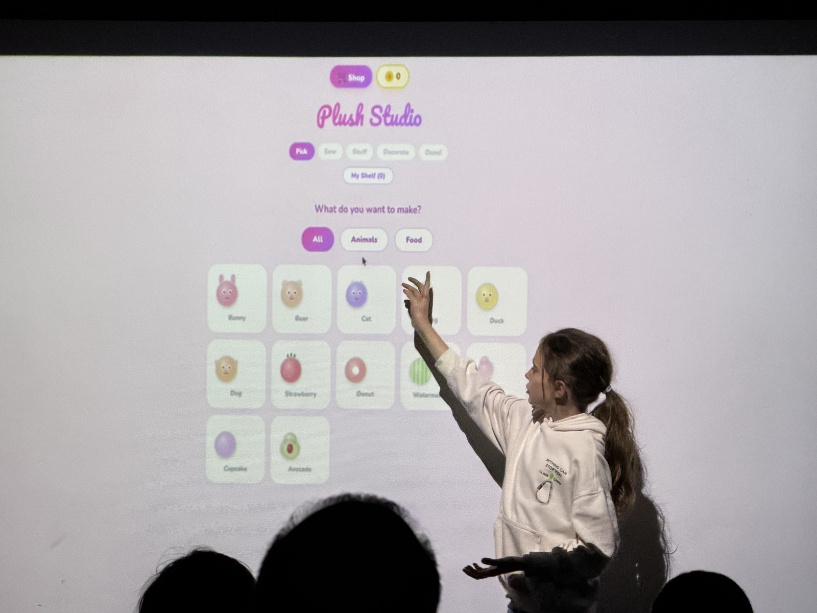 Lara presentando Plush Studio, señalando su app en la pantalla