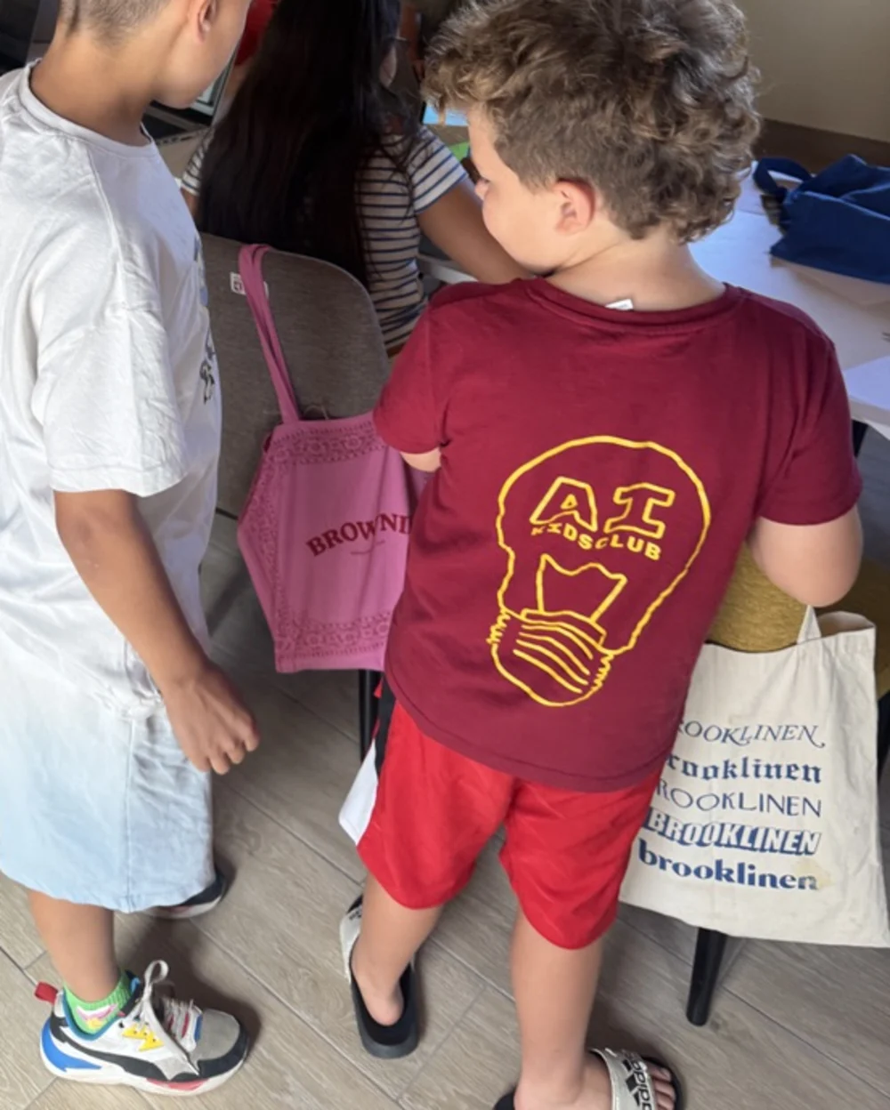 Two boys in the aula at Santibáñez, seen from behind, with the rest of the teams working at laptops around the table